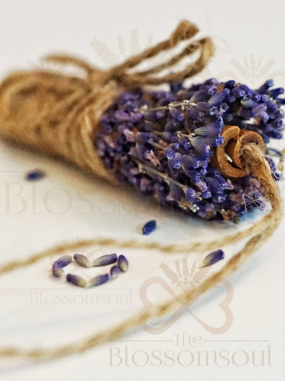 Close-up of handcrafted dried lavender and cinnamon botanical design tied with jute twine, with scattered lavender buds forming a heart on a white background.