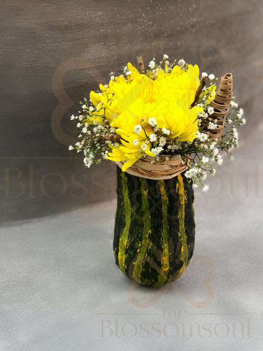 Artistic digital botanical artwork featuring a yellow chrysanthemum, baby’s breath flowers, and coconut sticks arranged in a green decorative pumpkin. Handcrafted and photographed in Dubai.