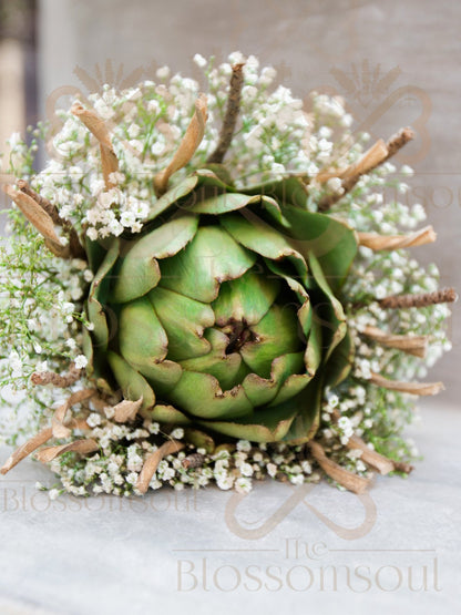 High-resolution digital artwork featuring a handcrafted natural bouquet with a green artichoke at the center, surrounded by delicate gypsophila and rustic coconut sticks. A minimalist and sustainable floral composition captured in soft natural lighting.